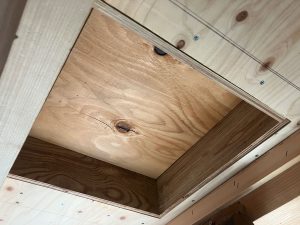 天井にある桁上断熱の居室面に空いた点検口の開口部と小屋裏床へ敷いた未開口の構造用合板