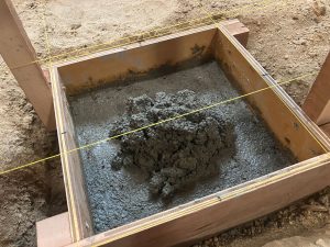 独立基礎用に作った型枠へコンクリートを50mm厚流し込み鏝で押さえ締めた上へ新しくコンクリートを盛り追加