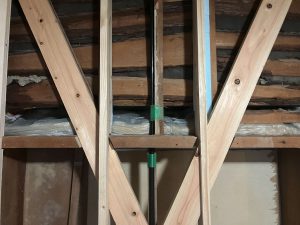 出窓庇屋根の上へ室内から袋入りロックウールを敷く