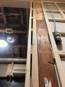 傾いた柱へ傾いた添え柱が付けられこれを内装としてカバー材をパッキン(スペーサー)当てて垂直を出してビス留めした柱および袖壁・垂れ壁