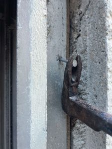 アルミサッシとモルタルの縁が切れたので木枠に留まっている釘をバールで抜く