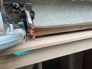 傾いている既存窓枠を垂直にするために丸ノコを窓枠上へ当ててカットする