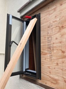 窓の入る部分を開口した窓枠に合わせて加工した12mm厚構造用合板の上から縦すべり出し窓を仮で付けてみる