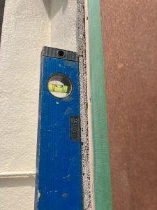 モルタルを削って垂直にした既存出窓モルタル枠に水平器を当てて確認中