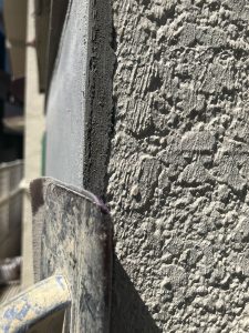 既存の出窓へ新しいモルタルを角を出しつつ垂直へ塗ったモルタル壁の角へ破損防止のため紙ヤスリをかける