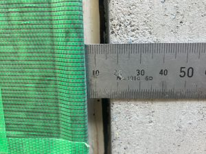 取り替えた窓と塗り直したモルタル壁との間のコーキング目地幅を鋼製定規で測定