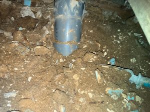 大量の土と木片・モルタル片を撤去中のトイレ床下 掘っていると排水管が見えてきた